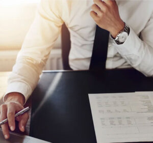 man in tie at a desk with paperwork and a calculator